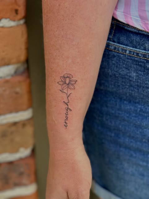 Fine line flower and encourage lettering tattoo on an arm